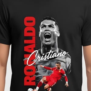 May include: Black t-shirt featuring a graphic of Cristiano Ronaldo in action. The design includes a large portrait and a smaller action shot, with the name "Ronaldo" in red vertical text and "Cristiano" in white script.