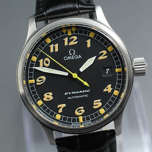 May include: An Omega Dynamic Automatic wristwatch with a black dial, yellow Arabic numerals, and a date window at the three o'clock position. The watch features a stainless steel case, luminous hands, a yellow second hand, and a black leather strap.