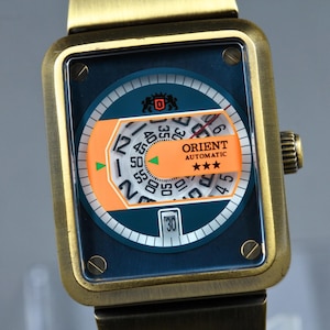 May include: A vintage Orient Automatic watch with a rectangular gold-tone case. The watch face is blue and orange, with white numerals and hands. The watch band is dark brown.