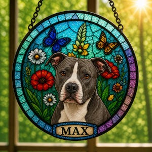 May include: Round stained glass window featuring a dog with the name "MAX". The artwork includes colorful flowers, butterflies, and a blue background. The window is framed with a black chain for hanging.