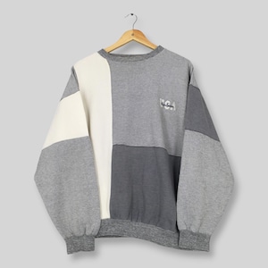 Könnte beinhalten: Ein langärmeliges Sweatshirt mit Rundhalsausschnitt und einem Color-Block-Design in Grau-, Anthrazit- und Off-White-Tönen. Das Kleidungsstück hat eine strukturierte Stoffoberfläche und enthält den gestickten Schriftzug USA auf der rechten Brust.