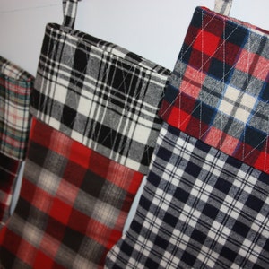 May include: Four Christmas stockings made from plaid fabric in red, black, white, and blue.