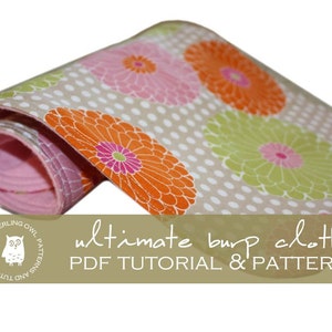 Könnte beinhalten: Ein zusammengerolltes rosa-weißes Spucktuch mit einem Blumenmuster in Orange-, Rosa- und Grüntönen. Der Stoff hat ein weißes Punkte-Muster. Der Text "ultimate burp cloth PDF TUTORIAL & PATTERN" ist auf einem braunen Banner unter dem Tuch gedruckt.