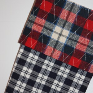 May include: A red, white and blue plaid Christmas stocking with a quilted design. The stocking is made of flannel fabric and has a loop at the top for hanging.