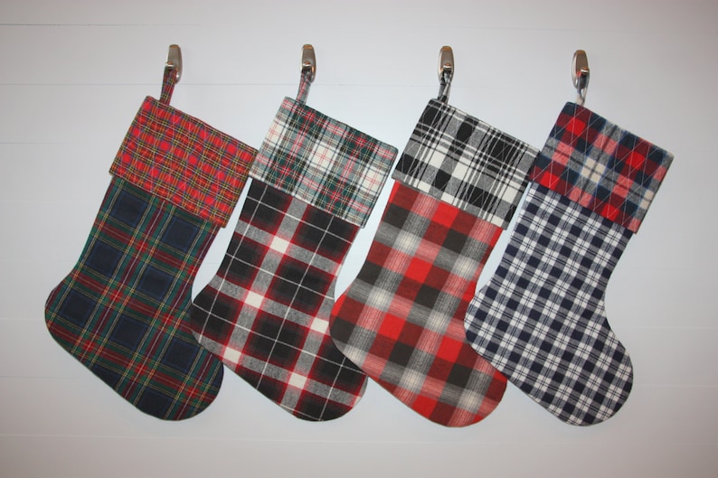 May include: Four Christmas stockings with different plaid patterns. The stockings are red, black, white, and blue.