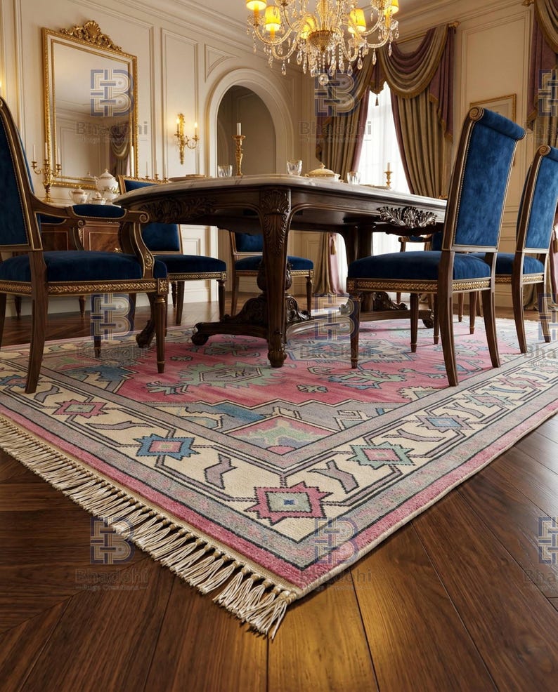 K&ouml;nnte beinhalten: Ein Esszimmer mit einem gro&szlig;en, verzierten Tisch und blauen Samtst&uuml;hlen. Ein gemusterter Teppich in Rosa-, Blau- und Cremet&ouml;nen bedeckt den Boden. &Uuml;ber dem Tisch h&auml;ngt ein Kronleuchter, und ein Spiegel ist sichtbar.