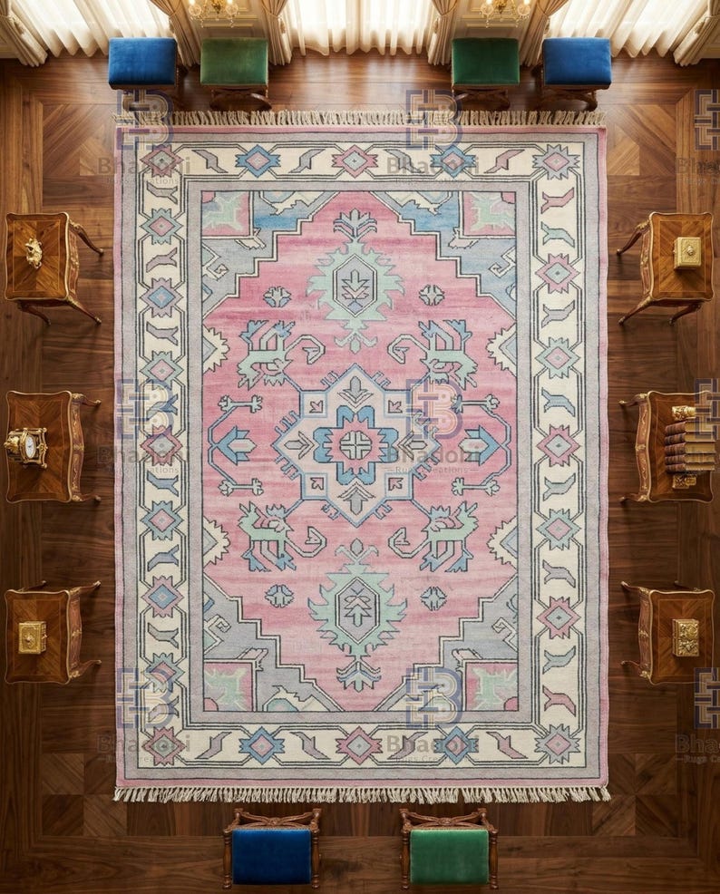 K&ouml;nnte beinhalten: Draufsicht auf einen rechteckigen, rosafarbenen Teppich mit einem detaillierten geometrischen Muster in Blau-, Grau- und Wei&szlig;t&ouml;nen. Der Teppich hat einen Fransenrand und ist von Holzm&ouml;beln und kleinen St&uuml;hlen umgeben.