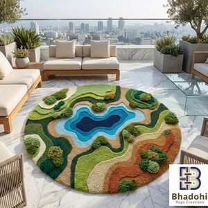 May include: A round, landscape-themed rug with a lake design. The rug features a central dark blue lake surrounded by layers of green, brown, and tan terrain. Small, tufted green trees are scattered across the landscape. The rug is placed on a marble patio.