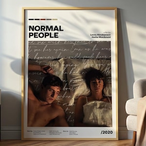 Puede incluir: Un póster enmarcado de "Normal People" con un marco de madera clara. El póster muestra a dos personas en la cama, con el título y los créditos en la parte superior. El año 2020 está en la parte inferior.