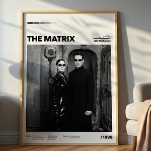 May include: A framed movie poster for "The Matrix" in a room setting. The black and white poster features two figures in sunglasses. The title "THE MATRIX" is displayed prominently. The poster is in a wooden frame.