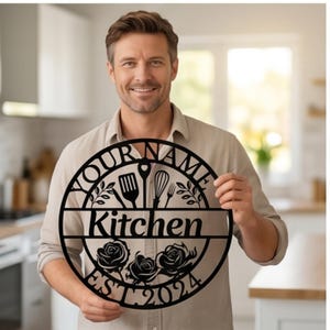 May include: Black metal kitchen sign with the text "YOUR NAME" at the top, "Kitchen" in the middle, and "EST. 2024" at the bottom. The sign features kitchen utensils and rose designs. The sign is round.