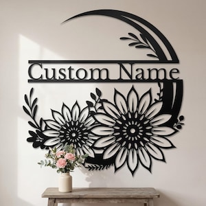 May include: Black metal wall art featuring a floral design with two large sunflowers and the text "Custom Name". The artwork includes a curved top element and decorative leaves, suitable for home decor.