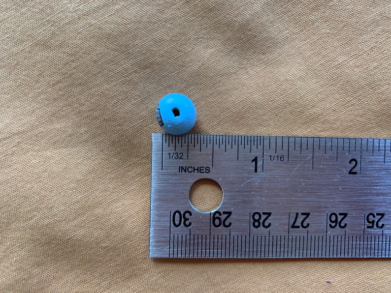 Puede incluir: Una cuenta de madera azul claro que mide aproximadamente 1,25 cm de di&aacute;metro. La cuenta est&aacute; al lado de una regla para referencia de tama&ntilde;o.