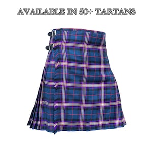 Puede incluir: Un kilt de tartán azul, morado y negro con un diseño plisado y dos hebillas. El texto "AVAILABLE IN 50+ TARTANS" está presente. El kilt está hecho de tela tejida.