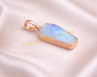 Op de afbeelding: Een roségouden hanger met een doodskistvormige maansteen. De maansteen heeft een blauw-witte iriserende gloed. De hanger ligt op een witte satijnen ondergrond. De tekst "Indus Jewels" is zichtbaar.