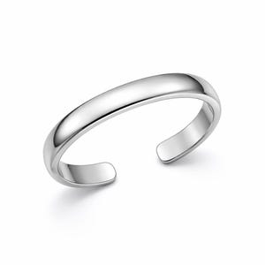 Puede incluir: Un anillo de puño plateado pulido con una parte superior lisa y redondeada y extremos abiertos. El anillo tiene un diseño simple y minimalista, que refleja la luz y crea una apariencia brillante. Este anillo ajustable es una joya.