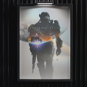 Peut inclure: Affiche encadrée représentant une silhouette de soldat futuriste avec le texte "REMEMBER REACH". L'œuvre d'art intègre une scène de coucher de soleil et un groupe de personnages, sur fond blanc lumineux.