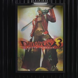 May include: Framed poster featuring a character from Devil May Cry 3, with the game's title and "Dante's Awakening" text. The character is in a red jacket, holding a large weapon. The background is a mix of colors.