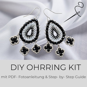 Könnte beinhalten: Ein Paar tropfenförmige Perlenohrringe mit schwarzen und weißen Saatperlen und hängenden vierblättrigen Kleeblatt-Akzenten. Der Text DIY OHRRING KIT mit PDF- Fotoanleitung & Step- by- Step Guide ist unten im Bild deutlich zu sehen.