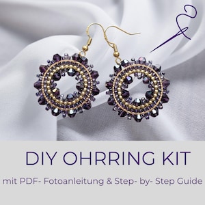 Könnte beinhalten: Handgefertigte Ohrringe mit kreisförmigem Design. Sie haben goldfarbene Metallrahmen, kleine goldene Perlen und dunkelviolette facettierte Perlen. Der Text "DIY OHRRING KIT" ist in Lila dargestellt.