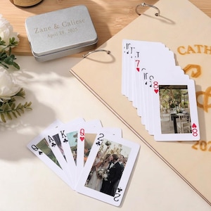 Puede incluir: Una baraja de cartas con fotos de boda, abanicadas sobre una superficie clara. Una caja plateada con la inscripción "Zane & Caliese April 19, 2025" está en el fondo. Las cartas presentan fotos y símbolos de cartas tradicionales.