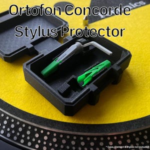 Può includere: Custodia protettiva per stilo Ortofon Concorde nera con uno stilo verde e bianco e una clip verde. La custodia è aperta, rivelando lo stilo e la clip all'interno. Il testo "Ortofon Concorde Stylus Protector" è in alto.