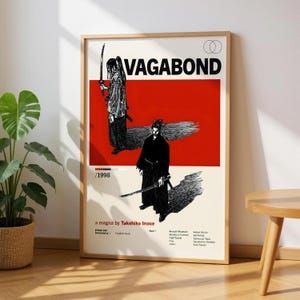 May include: Framed poster featuring the word "VAGABOND" in bold black letters above a red rectangle. The poster includes two black and white illustrations of samurai figures with swords. Text at the bottom reads "a magna by Takehiko Inoue."