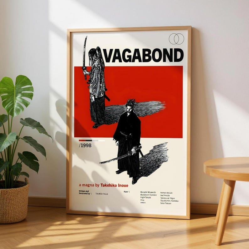 May include: Framed poster featuring the word "VAGABOND" in bold black letters above a red rectangle. The poster includes two black and white illustrations of samurai figures with swords. Text at the bottom reads "a magna by Takehiko Inoue."