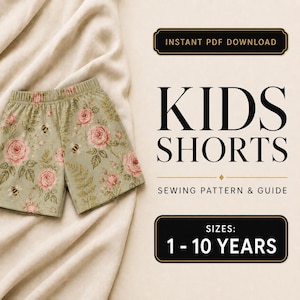 May include: An instant PDF download sewing pattern and guide for kids shorts in sizes 1-10 years. The image features a pair of sage green shorts with a floral pattern of pink roses and small bees, displayed on a light beige fabric background.