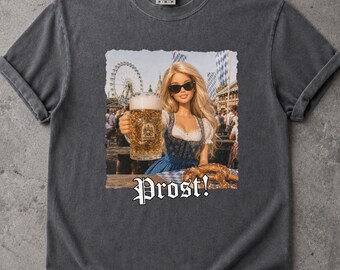 May include: A charcoal gray short-sleeve t-shirt featuring a graphic print of a blonde doll wearing sunglasses and a blue dirndl, holding a large glass beer mug. The text "Prost!" is printed in white below the image, which shows a fairground.