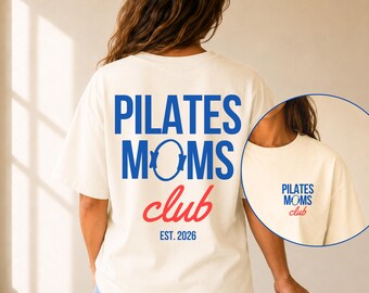 May include: An ivory short-sleeve t-shirt featuring blue and red text on the back that reads PILATES MOMS club EST. 2026, with a circular graphic replacing the letter O in MOMS. A smaller version of this design is printed on the front left chest.