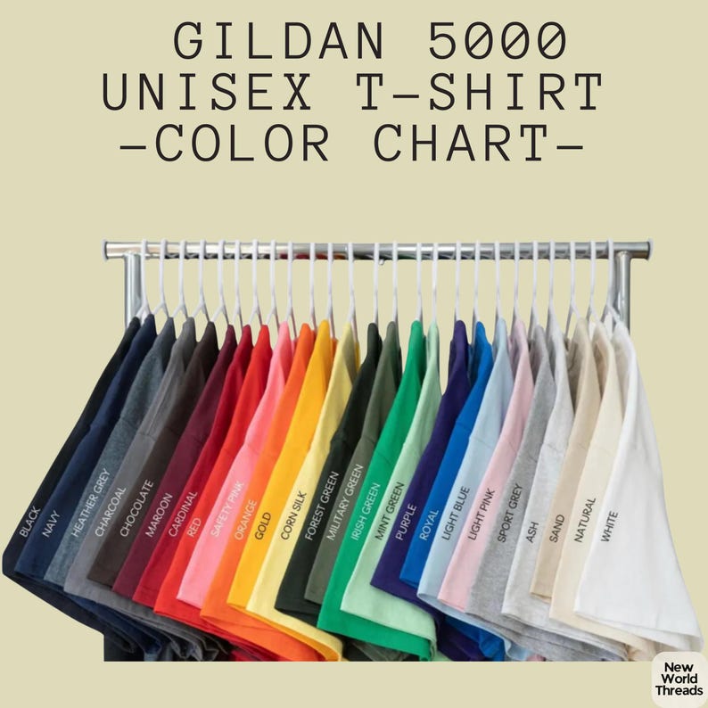 May include: A Gildan 5000 unisex t-shirt color chart displaying a wide variety of short-sleeved shirts hanging on a metal rack. The shirts are arranged in a spectrum of colors including black, navy, red, orange, yellow, green, blue, pink, gray, and white, with each color labeled clearly below the fabric.