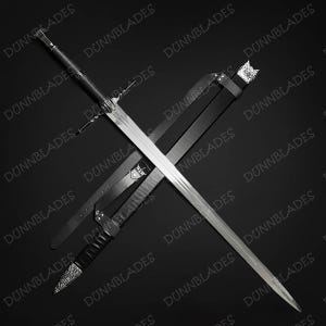May include: A long steel sword with a cross-shaped guard and a black leather-wrapped handle, positioned diagonally across a black leather scabbard. The scabbard features a silver-coloured metal chape at the tip and a matching silver locket at the top.