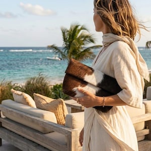 Handcrafted large leather clutch bag made from genuine tri-color hair-on-hide cowhide, featuring a modern foldover design in natural brown, black, and white tones for a western boho aesthetic. gift for her, gift for sister, gift for mother, personalized gift, custom handmade gift, trendy fashion