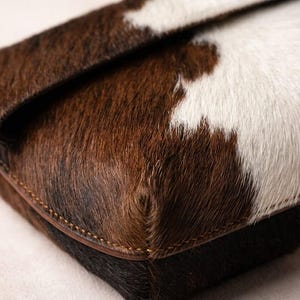 Handcrafted large leather clutch bag made from genuine tri-color hair-on-hide cowhide, featuring a modern foldover design in natural brown, black, and white tones for a western boho aesthetic. gift for her, gift for sister, gift for mother, personalized gift, custom handmade gift, trendy fashion