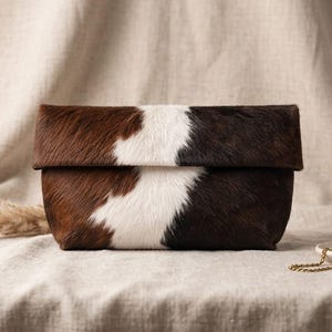 Handcrafted large leather clutch bag made from genuine tri-color hair-on-hide cowhide, featuring a modern foldover design in natural brown, black, and white tones for a western boho aesthetic. gift for her, gift for sister, gift for mother, personalized gift, custom handmade gift, trendy fashion