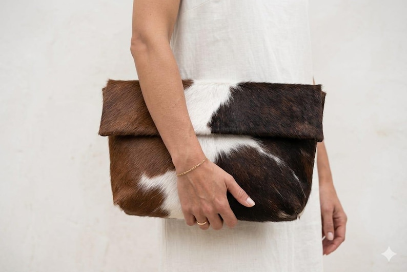 Handcrafted large leather clutch bag made from genuine tri-color hair-on-hide cowhide, featuring a modern foldover design in natural brown, black, and white tones for a western boho aesthetic. gift for her, gift for sister, gift for mother, personalized gift, custom handmade gift, trendy fashion
