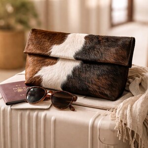 Handcrafted large leather clutch bag made from genuine tri-color hair-on-hide cowhide, featuring a modern foldover design in natural brown, black, and white tones for a western boho aesthetic. gift for her, gift for sister, gift for mother, personalized gift, custom handmade gift, trendy fashion