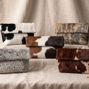 Handcrafted large leather clutch bag made from genuine tri-color hair-on-hide cowhide, featuring a modern foldover design in natural brown, black, and white tones for a western boho aesthetic. gift for her, gift for sister, gift for mother, personalized gift, custom handmade gift, trendy fashion