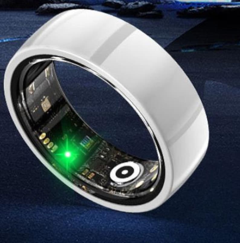 May include: A smart ring with a glossy white exterior and a dark interior. The inside of the ring features a circuit board design with a bright green light. The ring has a sleek, modern design.