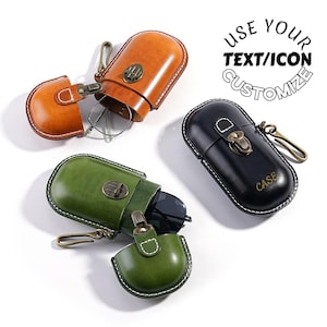 Puede incluir: Tres estuches de cuero para gafas en marrón, verde y negro. Cada estuche está abierto, revelando su contenido. El estuche marrón contiene gafas, el estuche verde contiene gafas de sol y el estuche negro tiene la palabra "CASE" impresa. Cada estuche tiene un cierre metálico y un mosquetón dorado.