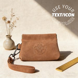Könnte beinhalten: Eine braune Wildledertasche mit geprägtem Blumendesign. Die Tasche hat eine Handschlaufe und einen Metallverschluss. Der Text "USE YOUR TEXT/ICON CUSTOMIZE" befindet sich oben rechts. Eine kleine Vase mit getrockneten Blumen und ein Messinglineal sind ebenfalls im Bild.