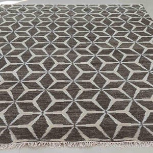 May include: A rectangular area rug with a geometric starburst pattern in shades of brown and off-white. The rug has a fringe along the edges and is suitable for a living room or bedroom. The rug is approximately 8 feet by 10 feet.