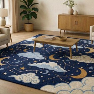 May include: A navy blue area rug featuring a celestial design with white clouds, gold crescent moons, and constellations. The rug is rectangular and placed in a living room setting with a sofa, armchair, and wooden furniture.