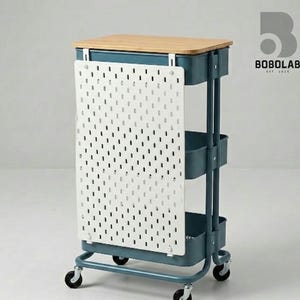 Könnte beinhalten: Ein tealfarbener Rollwagen mit einer hellen Holzplatte und drei Aufbewahrungsbehältern. Eine weiße Lochwand ist an der Seite befestigt. Der Wagen hat vier schwarze Räder und eignet sich zur Aufbewahrung.