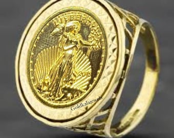 May include: A gold ring featuring a coin design with a woman holding a branch. The ring has a detailed filigree band and a textured bezel around the coin. The coin has the inscription "LIBERTY" and the year 2015.