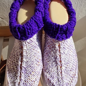 Könnte beinhalten: Ein Paar Strickpantoffeln mit einem violetten Bund und einem weißen und violetten Muster.