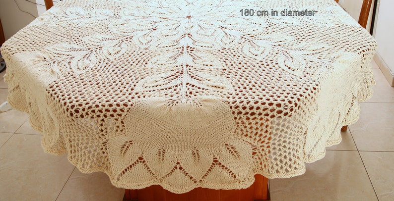 Puede incluir: Un gran mantel de crochet de color crema con un delicado patr&oacute;n floral. El mantel tiene un di&aacute;metro de 180 cm.