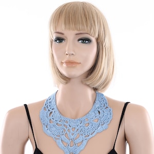 May include: A light blue crocheted collar necklace with a delicate floral pattern.
