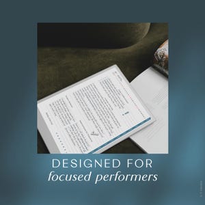 May include: A white notebook with a blue border and text, "Designed for focused performers." The notebook is open to a page with handwritten notes and a checklist. The background is a dark green.